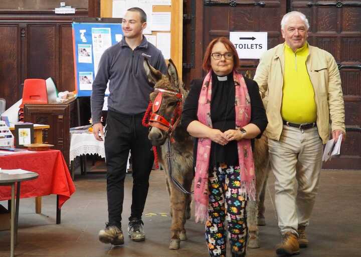 the reverend vet walking with a donkey during special pet service in 2024